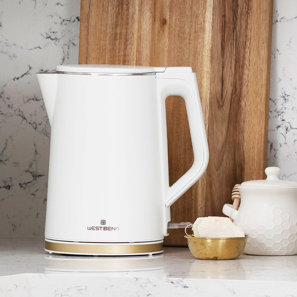 White electric kettle with gold base trim and side handle on countertop