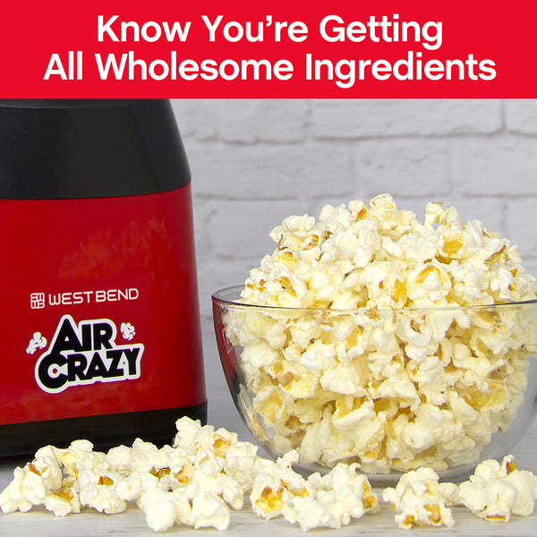 Red air popcorn machine with glass bowl filled with popped popcorn